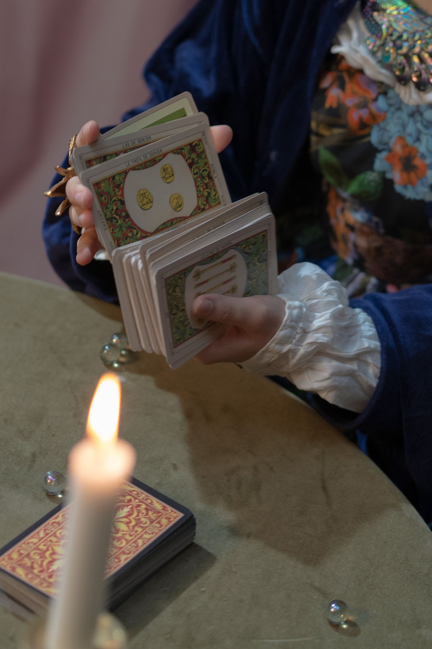 A reader gently shuffling tarot cards beside a candle